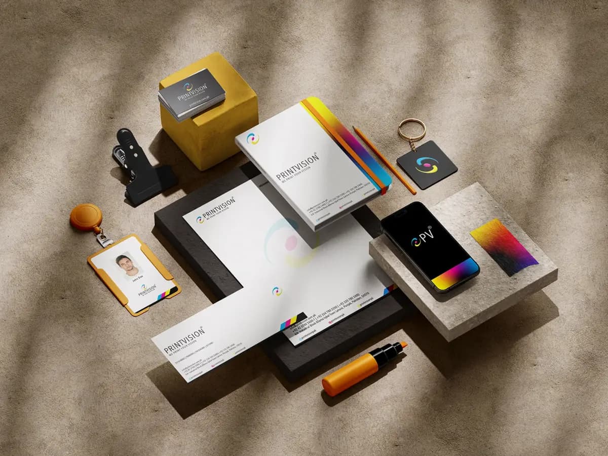 PrintVision stationery system: business cards, letterhead, company profile, ID badge, keyring and phone, all carrying the CMYK ribbon mark