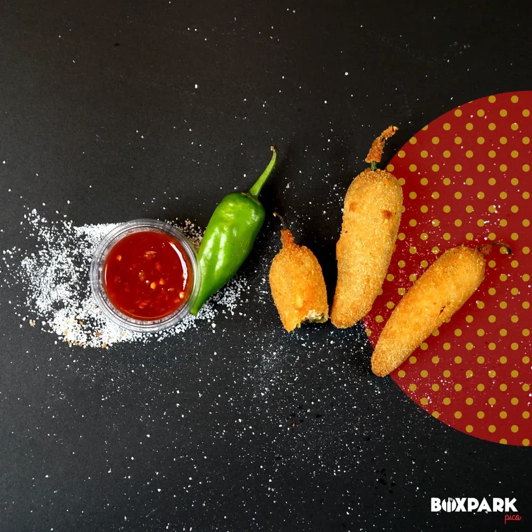 Corn dogs, chilli and ketchup on a dark set with scattered flour