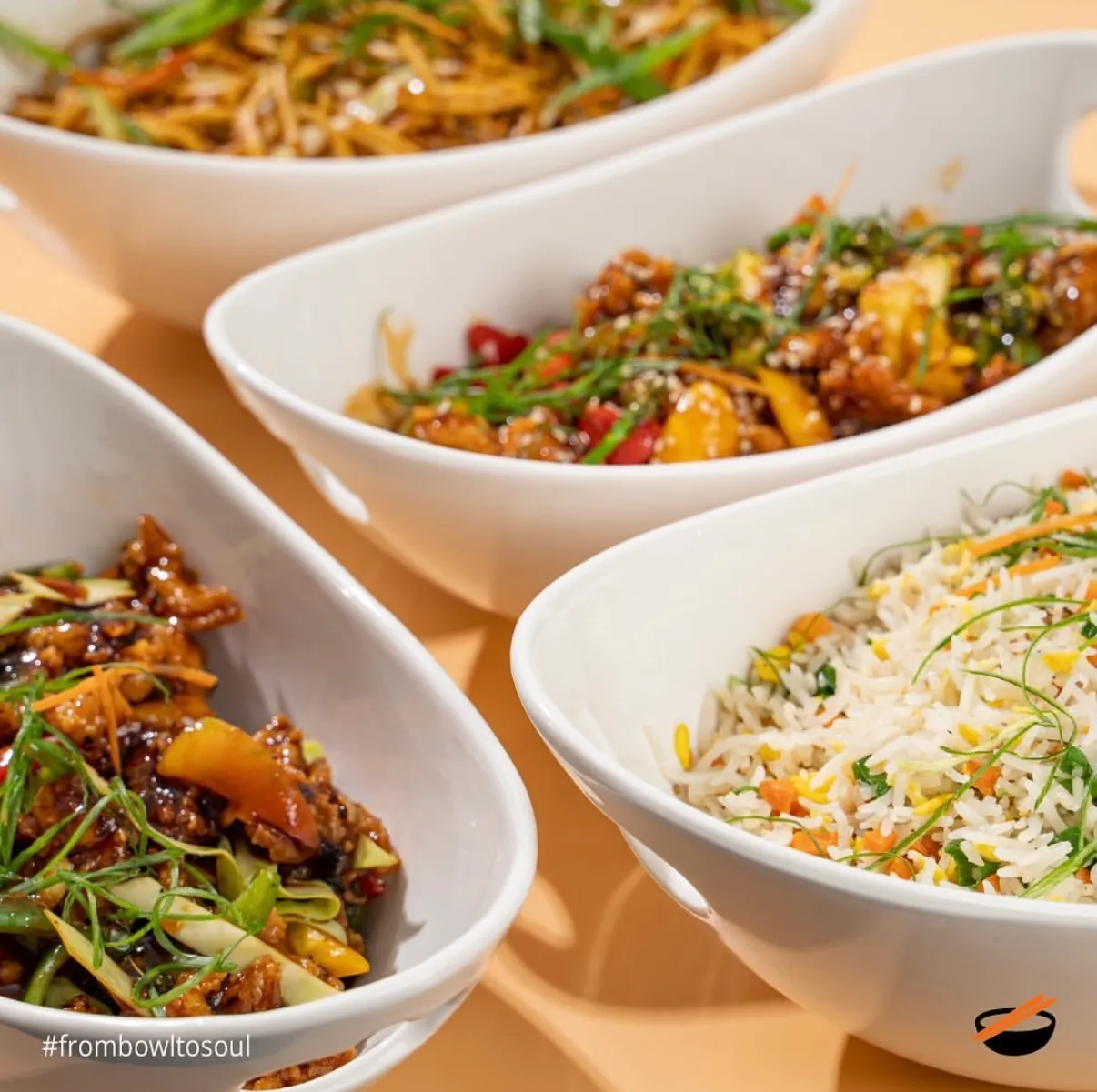 White bowls of noodles and rice photographed in a row on orange
