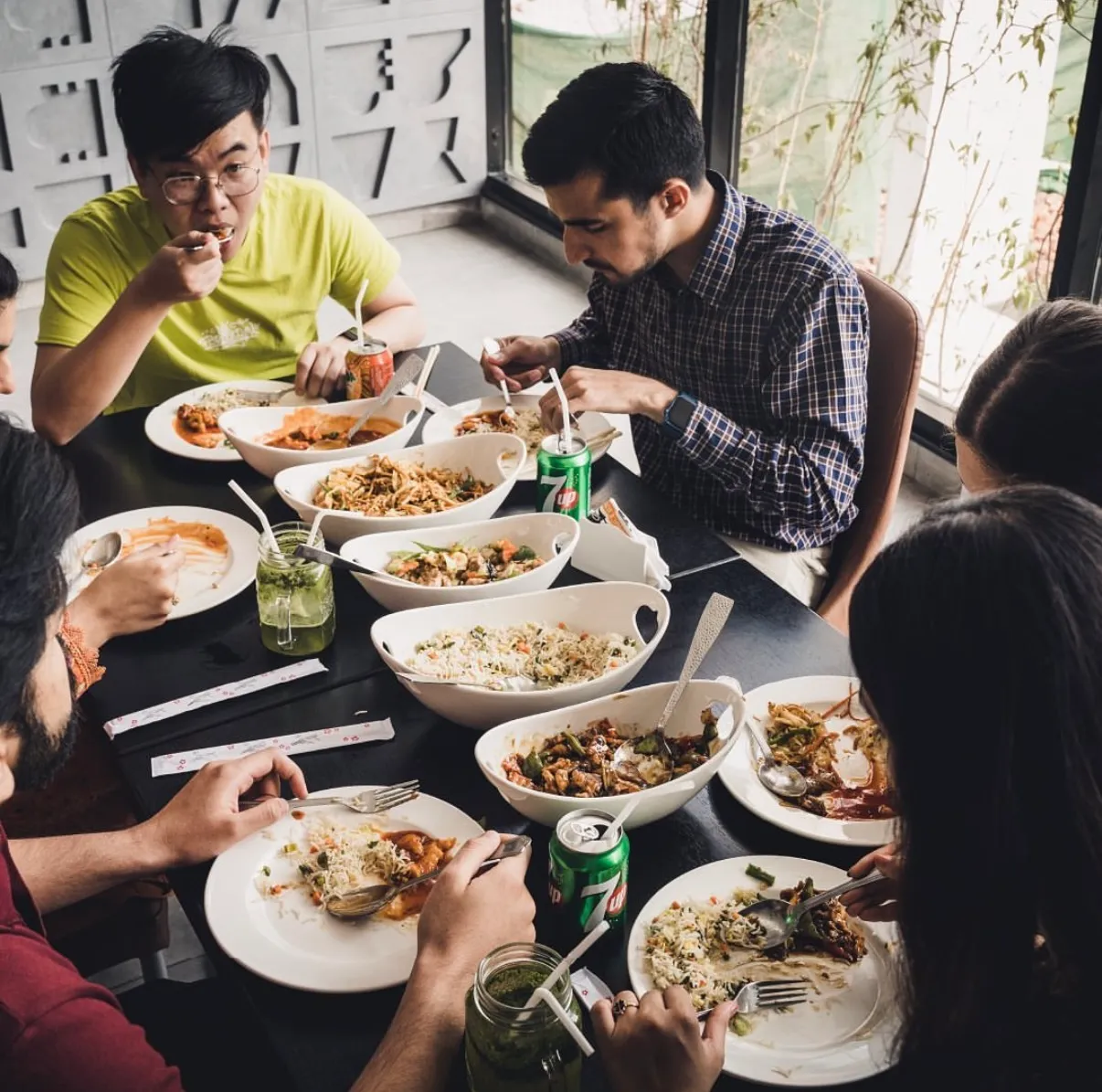 A long table of friends sharing Rice Bowl dishes in the restaurant