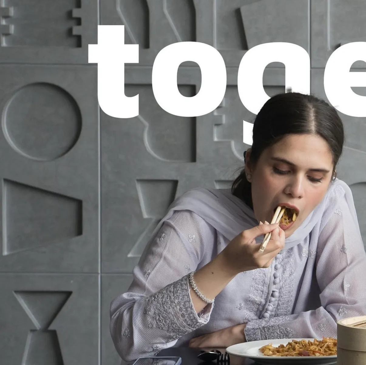 A woman eating from a bowl with chopsticks, the word togetherness spanning behind her